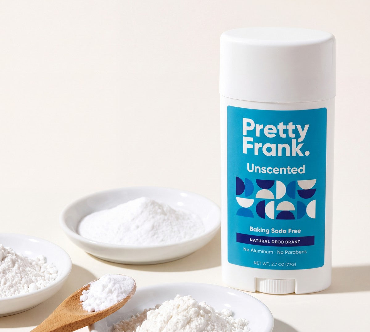 Pretty Frank Unscented baking soda free deodorant stick beside small dishes of white powder and a wooden spoon