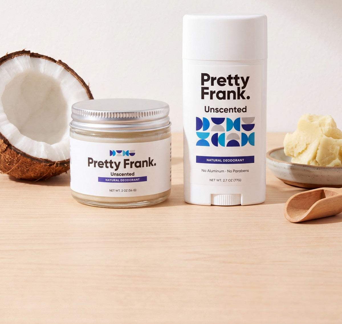 Pretty Frank Unscented deodorant jar and stick on a wooden table with a halved coconut and a dish of shea butter